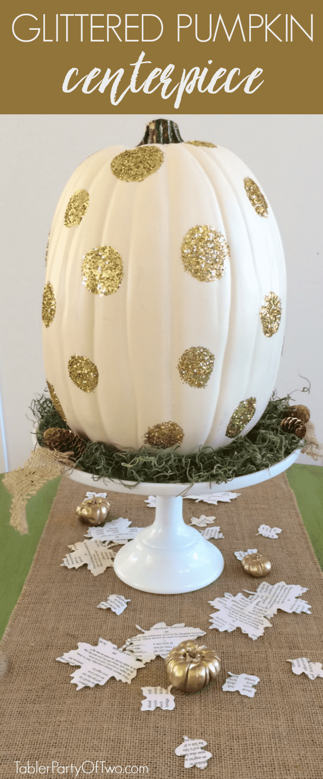 A large white pumpkin with gold glitter on a white cake stand.
