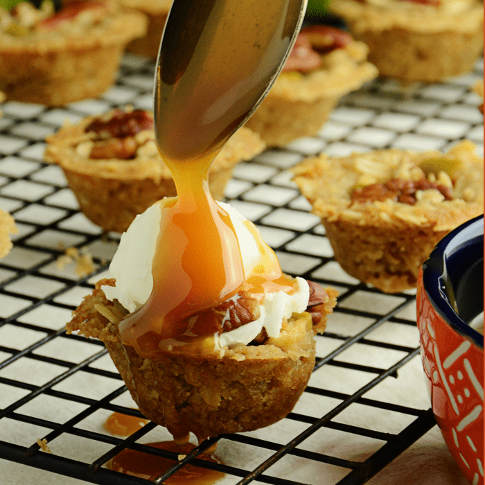 Mini apple crisps square with caramel sauce being poured over top.