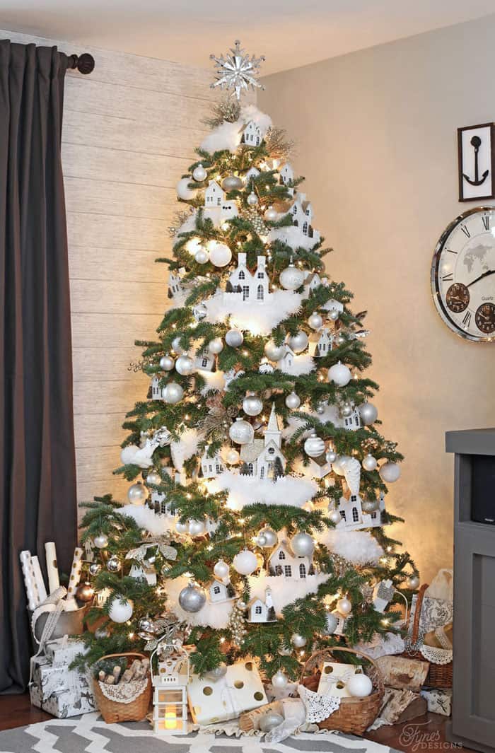 A tree with pops of white houses and silver ornaments.