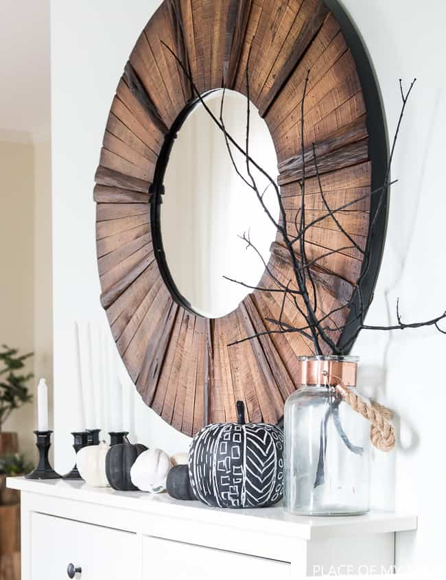 wood mirror in entry way with black and white pumpkins