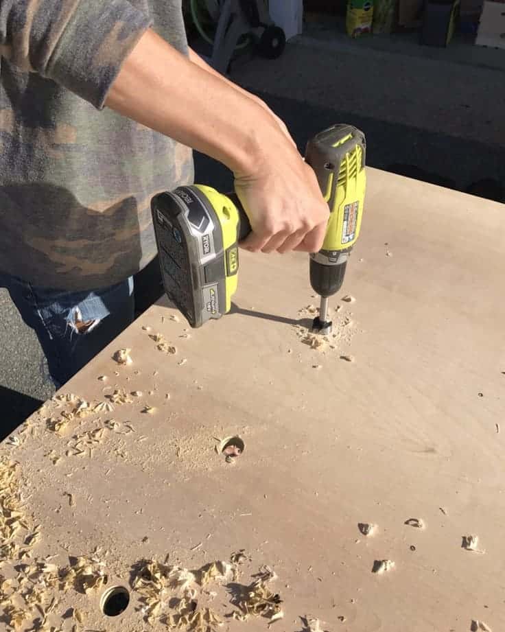 Perforar agujeros en la madera contrachapada para la pared gigante de tableros de clavijas