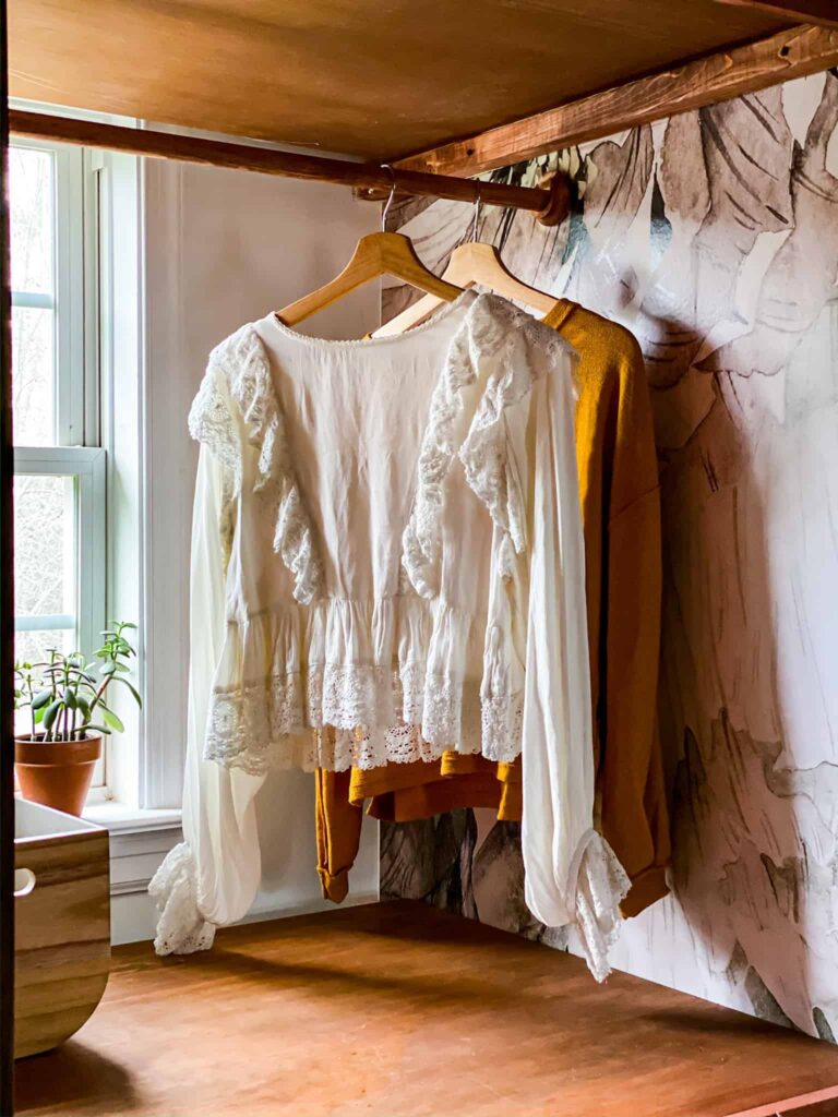 Small Laundry Room makeover. I love the stacked washer and dryer, the dramatic peel and stick wallpaper and penny tiles in this laundry room. The DIY Shelving around washer and dryer is brilliant . And talk about that macrame curtain...! Wow. Such a great laundry room makeover.