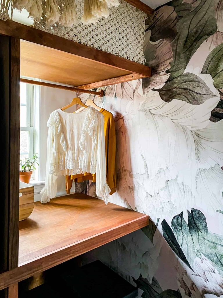 Small Laundry Room makeover. I love the stacked washer and dryer, the dramatic peel and stick wallpaper and penny tiles in this laundry room. The DIY Shelving around washer and dryer is brilliant . And talk about that macrame curtain...! Wow. Such a great laundry room makeover.