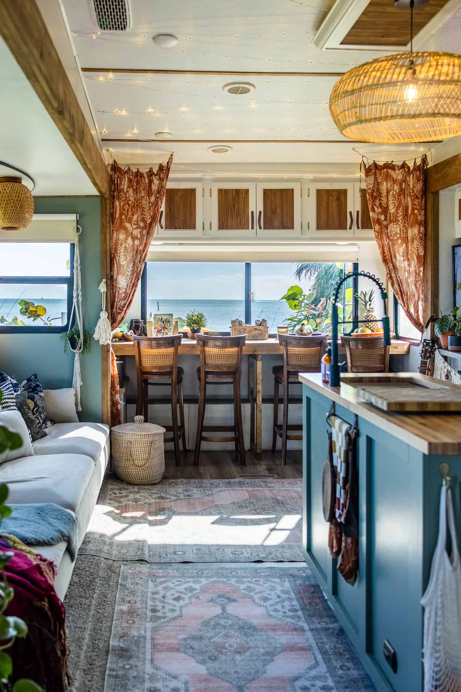 Amazing camper renovation with brown woodsy features, rustic chairs and colorful rugs.