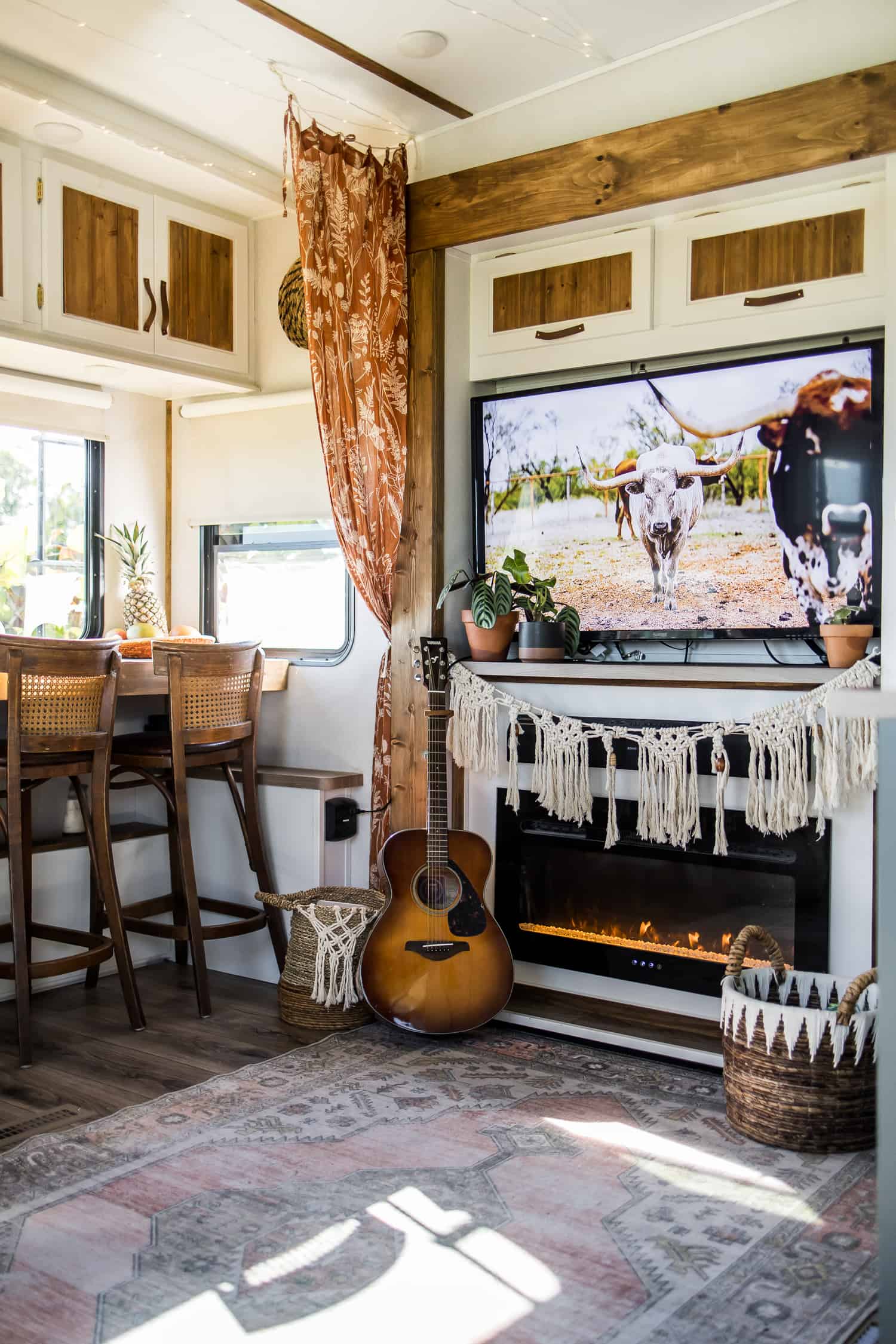 Large TV with macrame garland underneath in camper's living space.